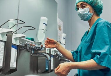 A healthcare worker sanitizer their hands with an OPHARDT ingo-man dispenser.